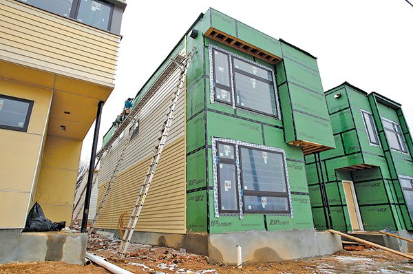 Siding is placed on single-family houses and duplexes 
Thursday at the intersection of West Avenue and Prairie Street in Fayetteville. The new construction by Jacobs & Newell Co. has a variety of “green” features, such as efficient insulation, low-flow faucets, recycled material or solar panels.