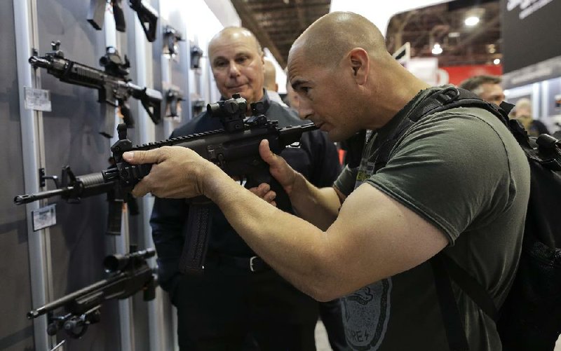 John Montenegro of the Los Angeles Police Department SWAT team examines a Sig Sauer MPK-K short barrel submachine gun Tuesday during the Shooting, Hunting and Outdoor Trade Show in Las Vegas. 