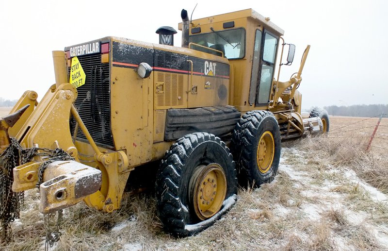 TIMES photograph by Annette Beard A Benton County road grader came to rest across a barbed wire fence in a field on the north side of Lee Town Road Wednesday, Jan. 8. The driver, Stanely Drain, was taken to Mercy Medical Center by ambulance.