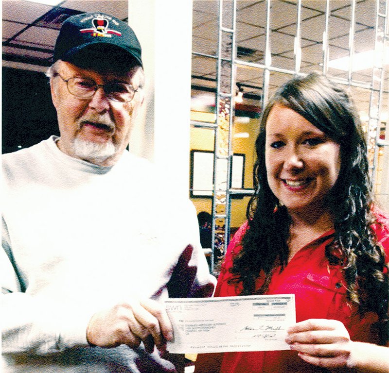 Dave Hellerich of Conway, adjutant of the John H. Dunn Disabled American Veterans Chapter 10, accepts a check for $2,000 from Tabitha Scott, an employee of Southwestern Energy. Hellerich said the money, from the Community Heroes program, will be put toward a project to connect the DAV building’s septic system to the city’s sewer line.