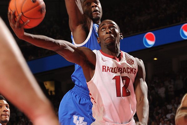 Arkansas guard Fred Gulley (12) scores around Kentucky forward Julius Randle, top, and guard Aaron Harrison during the first half of play Tuesday, Jan. 14, 2014, in Bud Walton Arena in Fayetteville.