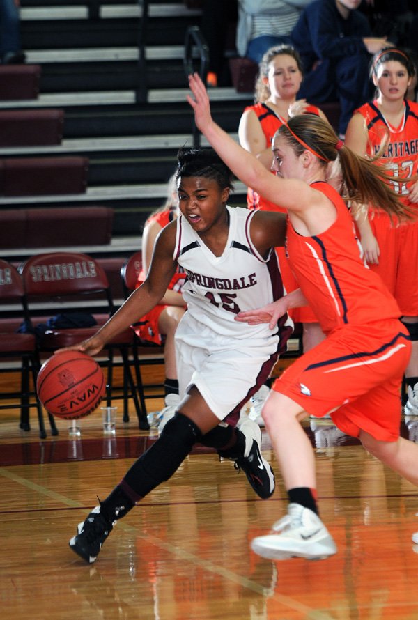 Javonda Daniels, left, of Springdale drives past Emilie Jobst of Rogers Heritage Tuesday, Jan. 14, 2014, during the firs half of the game at Bulldog Gym in Springdale.