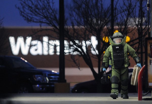 Cpl. Kerry Pippin with the Bentonville Bomb Squad removes a suspicious suitcase at the Murphy's USA gas station Thursday, Jan. 16, 2014, located near Walmart on Walnut Street in Rogers. Police say after determining the case was safe, it was opened and found to be empty.