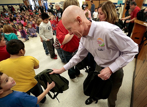 Dave Smith with Kids in Need Foundation helps distribute new backpacks filled with school supplies on Friday, Jan. 17, 2014, at Grace Hill Elementary School in Rogers. Representatives from 3M and Kids in Need Foundation distributed 550 backpacks to the students from kindergarten to fifth grade.
