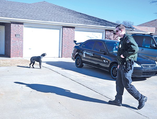STAFF PHOTO ANTHONY REYES 
Eric Cline, Springdale animal control officer, approaches a house Friday while responding to a call about a loose dog in Springdale. Springdale will soon start giving some compensation to employees on call, including animal control officers.