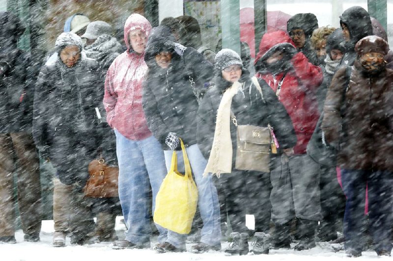 Commuters wait for a bus Tuesday in Philadelphia, where 10 to 14 inches of snow was forecast. 