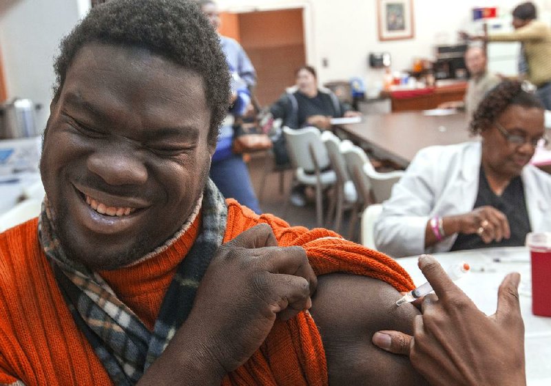 Nicholas Parker, 23, of North Little Rock grimaces as he gets a flu shot at a free mass clinic at the North Little Rock Health Department on Tuesday. There have been 23 flu deaths in Arkansas this season. 