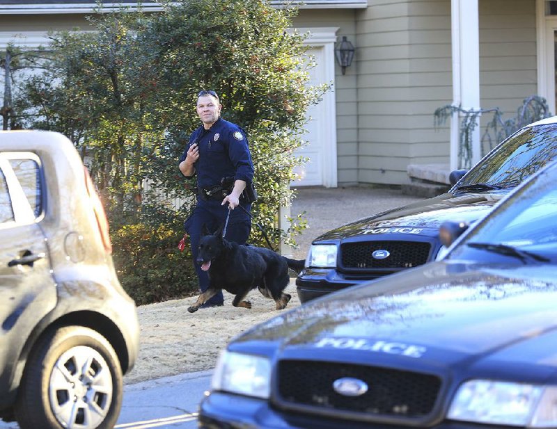 A Little Rock officer and a police dog search Tuesday for a suspect on Normandy Lane. The subject of the search was a Hall High School student who police say is wanted for attempted capital murder and robbery. Police said they did not find him.
