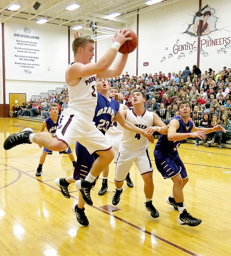 Photo by Randy Moll Gentry senior, Jarod Cousins, grabs a rebound in play against Ozark on Friday at Gentry High School. Jake Faulkenberry looks on to assist for Gentry. Ozark defenders below the basket are Blake Rofkahr (#23) and Jake Simpson (#5).