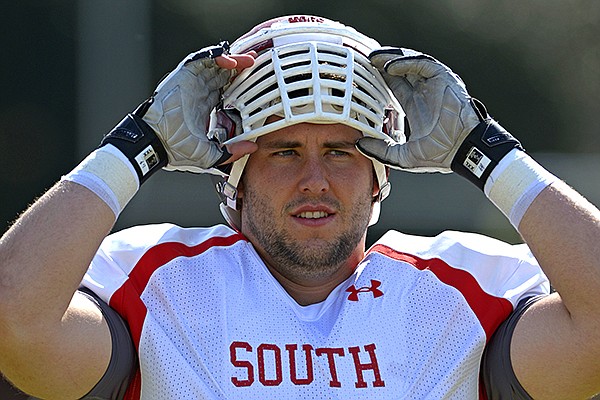 South Squad center Travis Swanson of Arkansas (64) puts on his helmet during Senior Bowl practice at Fairhope Municipal Stadium, Monday, Jan. 20, 2014 in Fairhope, Ala. (AP Photo/G.M. Andrews)