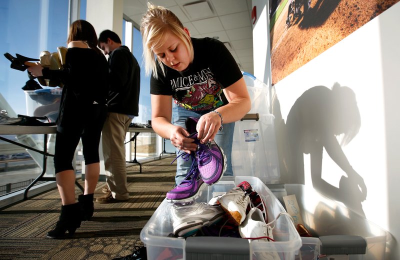 Volunteer Erin Sherman of Springdale sorts through and organizes shoes at Arvest Ballpark in 2013. The Walk A Mile In My Shoes … Sale on Friday and Saturday will benefit the Ozark Guidance Foundation. 