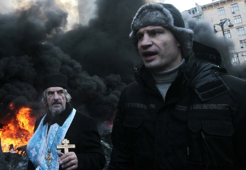 Opposition leader and former WBC heavyweight boxing champion Vitali Klitschko addresses protesters near the burning barricades between police and protesters in central Kiev, Ukraine, Thursday Jan. 23, 2014.   Klitschko dove behind the wall of black smoke engulfing much of downtown Kiev on Thursday, pleading with both police and protesters to uphold the peace until the ultimatum, demanding that Yanukovych dismiss the government, call early elections and scrap harsh anti-protest legislation that triggered the violence, expires Thursday evening. (AP Photo/Sergei Chuzavkov)