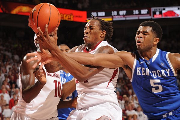 Arkansas guard Michael Qualls, center, and Kentucky guard Andrew Harrison (5) reach for a loose ball during overtime Tuesday, Jan. 14, 2014, in Bud Walton Arena in Fayetteville.