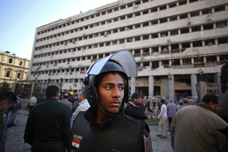 An Egyptian policeman stands guard after a car bomb attack at the Egyptian police headquarters in downtown Cairo on Friday, Jan. 24, 2014. Three bombings hit high-profile areas around Cairo on Friday, including a suicide car bomber who struck the city's police headquarters, killing several people in the first major attack on the Egyptian capital as insurgents step up a campaign of violence after the ouster of the Islamist president.