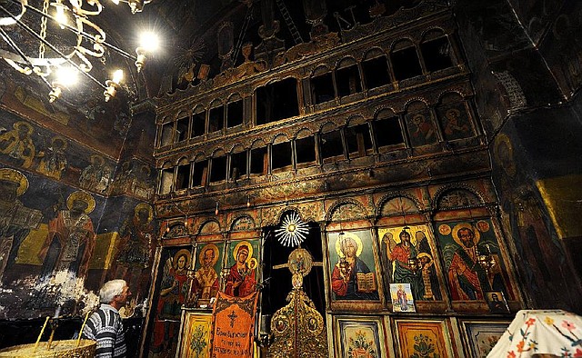 In this photo taken Thursday, Oct. 31, 2013, church guardian Mile Skrceski, left, looks at icon niches at the St. Nicholas church in village of Radozda, in southwestern Macedonia. Over the past decade, this small Balkan nation of 2.1 million has seen more than 10,000 religious artifacts stolen from its churches, including precious icons painted in the stylized Byzantine tradition. None of the works have been recovered. Thieves have removed whole sections of altar screens, altars, crosses, lamps and Bibles.