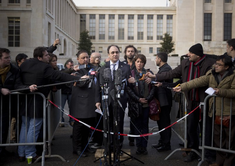 Monzer Akbik, center, a spokesman of the Syrian National Coalition, Syria's main political opposition group, is surrounded by journalists after a meeting with the Syrian government at the United Nations headquarters in Geneva, Switzerland, Sunday, Jan. 26, 2014. Syrians on opposite sides of their country’s civil war tried again Sunday to find common ground, with peace talks focusing on an aid convoy to a besieged city that once more came under mortar attack from the government. (AP Photo/Anja Niedringhaus)