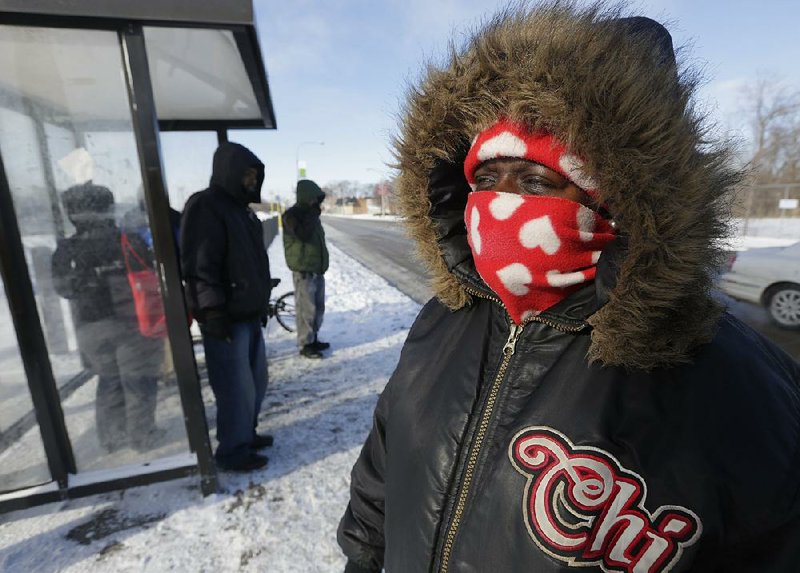 Charlita Lucious takes in what little warmth the sun gives off as she waits for her bus in sub-zero tempereatures, Monday Jan. 27, 2014 in Chicago. Meteorologists are predicting that the most recent cold snap caused by persistant cold winds, will keep temperatures below zero for what could be three days across the Midwest and beyond. (AP Photo/M. Spencer Green)