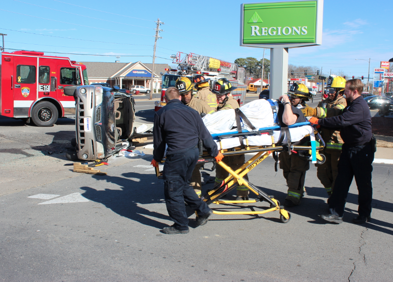 A driver is taken to an ambulance after being freed from his toppled sport utility vehicle.