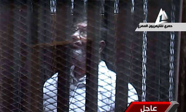Former President Mohammed Morsi stands Tuesday inside a glass-encased metal cage in a courtroom in Cairo in this image taken from Egyptian state TV. Morsi was separated from other defendants. 