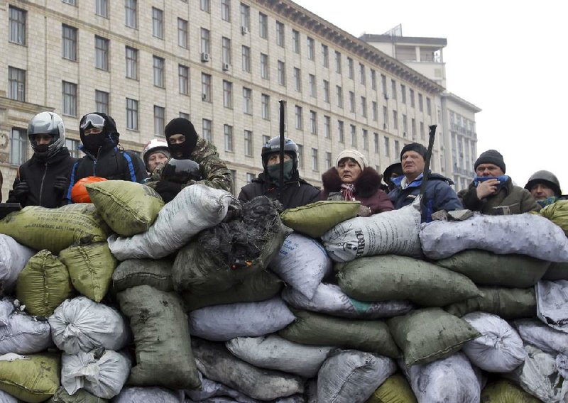 Protesters guard the barricade in front of riot police Tuesday in Kiev, Ukraine. Prime Minister Mykola Azarov submitted his resignation on Tuesday, saying he hoped the move would help bring a peaceful resolution to the crisis that has gripped the country for two months. 