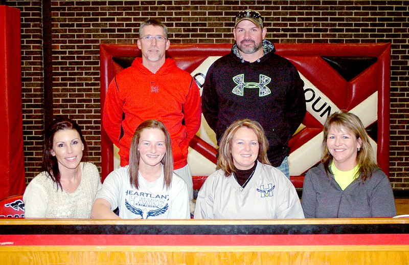 RICK PECK MCDONALD COUNTY PRESS Kelsy Reynolds (front row, second from left) signs a letter of intent to play softball at Heartland Community College in Normal, Ill. Front row, left to right: Haylee Hodson (friend), Reynolds, Paula Higgins (mom) and Dinah McCall (former MCHS softball coach). Back row: Lee Smith (assistant MCHS softball coach) and Tracy Hodson (friend).
