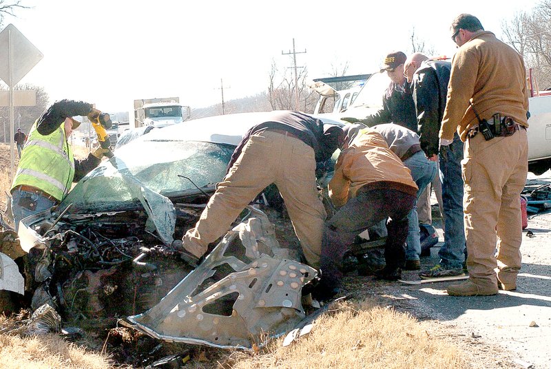 RICK PECK MCDONALD COUNTY PRESS Emergency personnel work to extricate the driver from her car after it collided nearly head-on with a tractor trailer Tuesday on Business Highway 71 in Anderson. Peggy Gilliam, 49, of Anderson, sustained serious injuries in the crash.