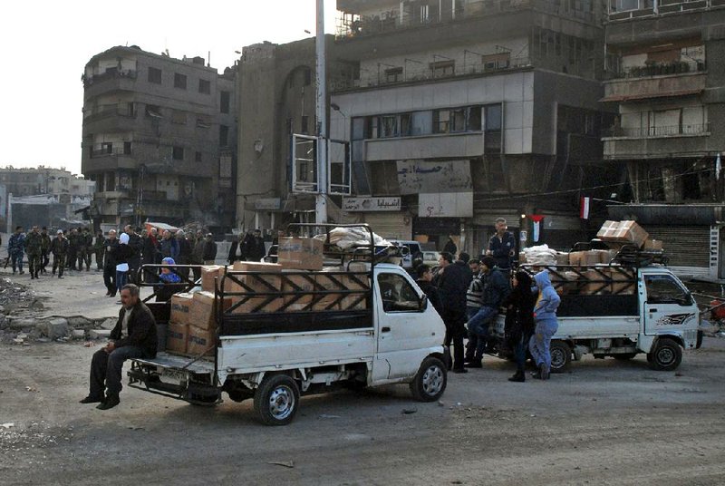 In this photo released by the Syrian official news agency SANA, trucks carry U.N. supplies at the besieged refugee camp of Yarmouk on the southern edge of the Syrian capital of Damascus, Syria, Thursday, Jan. 30, 2014. The U.N. says 600 food parcels were distributed in the camp where activists say at least 85 people have died as a result of lack of food and medicine since mid-2013. (AP Photo/SANA)
