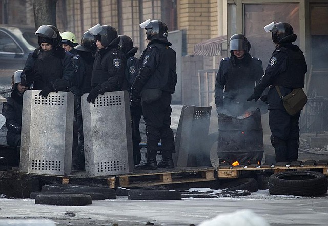 Riot police warm up near a barricade in central Kiev, Ukraine, Thursday, Jan. 30, 2014. Ukraine's embattled president Viktor Yanukovych is taking sick leave as the country's political crisis continues without signs of resolution. (AP Photo/Darko Bandic)