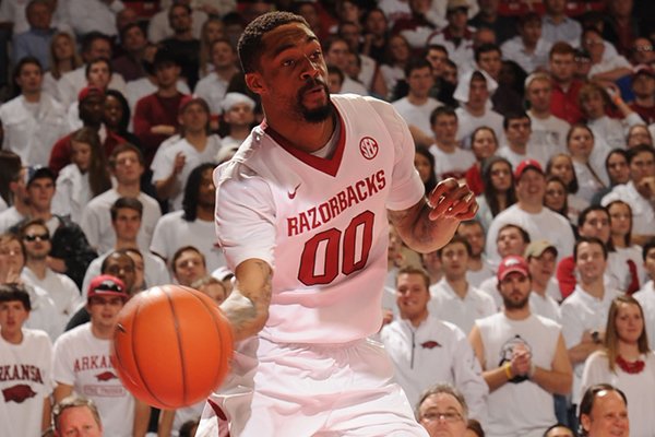 Arkansas guard Rashad Madden (00) passes around Kentucky center Dakari Johnson during the second half of play Tuesday, Jan. 14, 2014, in Bud Walton Arena in Fayetteville.