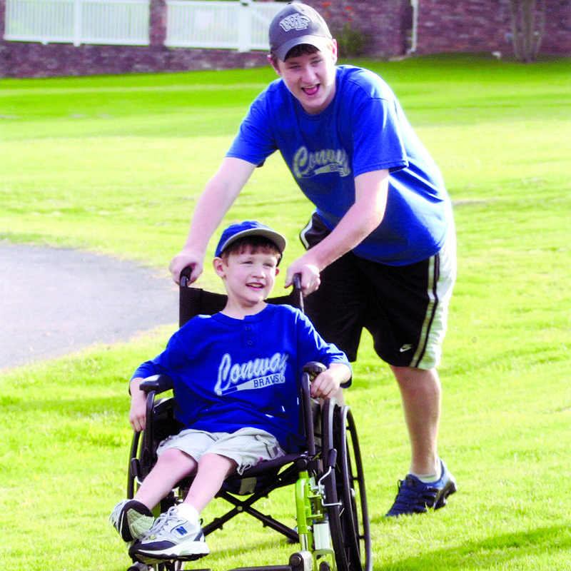 Will Patterson pushes his brother, Ben, at their home in Conway. Ben, who died in 2007, was a member of the Braves, a team for special-needs children. The team was started by the boys’ parents, Drs. Bill Patterson and Kim Mitchell. Fundraising is underway to build Braves Field at an existing Conway park, and the seating will be called Ben’s Bleachers.