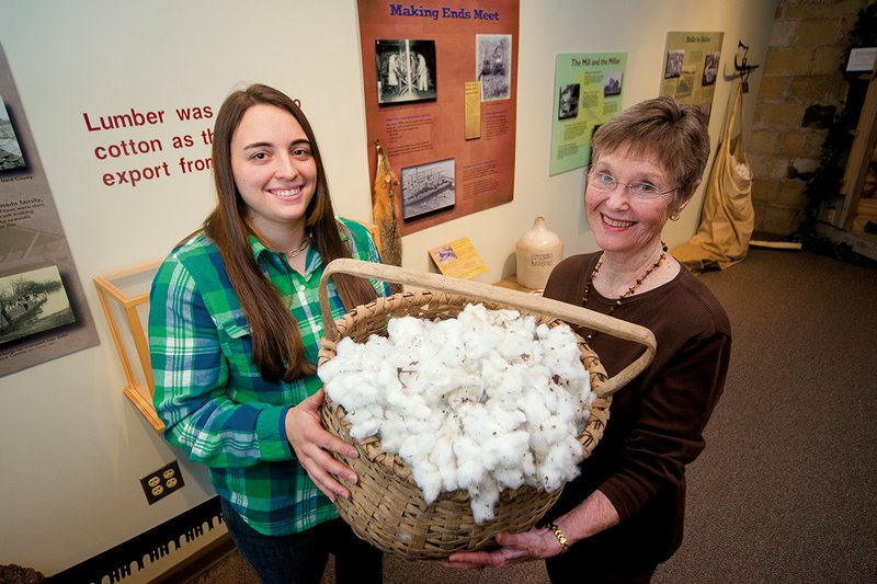 Amelia Bowman, left, a museum intern who is finishing her master’s degree in public history at Arkansas State University, and Twyla Wright, curator at the Old Independence Regional Museum in Batesville, are shown with a basket of cotton that is part of Earning a Living, an exhibit that opens at the museumFeb. 2.
