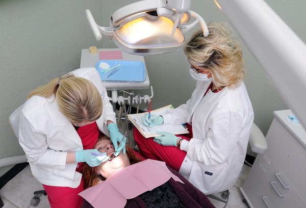 Amy Gephart, right, takes notes as Dr. Jill Self-Pike, left, examines Linda Smith Thursday, Jan. 30, 2014, at the Samaritan Community Center in Rogers. Due to a grant, the volunteer-run dental clinic will be expanding and will add Self-Pike and Gephart as part-time employees.  Self-Pike said the clinic offers exams, x-rays, extractions, fillings, cleanings, and a referral program for dentures.