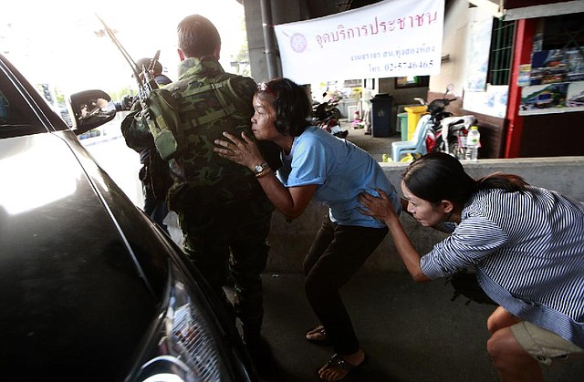 People take cover Saturday in Bangkok behind Thai soldiers who were sent to rescue them amid clashes between anti-government groups and government supporters. 