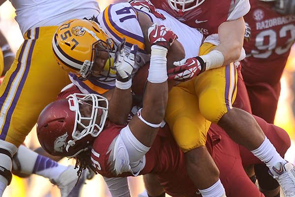 LSU running back Terrence Magee is taken down by Arkansas defenders Darius Philon and Brooks Ellis in the 2nd quarter of a Nov. 29, 2013 game at Tiger Stadium in Baton Rouge, La. 