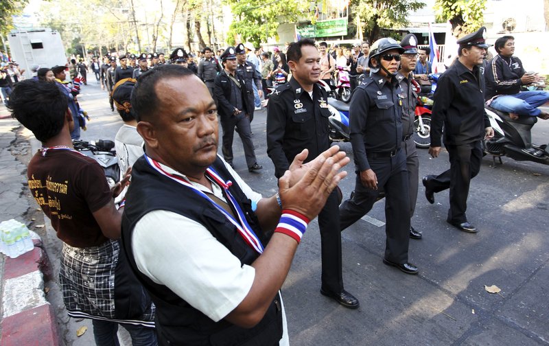 Anti-government protesters clap hands as Thai policemen walk in to take position between pro and anti elections group at Dindaeng district office in Bangkok, Thailand Sunday, Feb. 2, 2014. Thailand's tense national election got underway Sunday with protesters forcing the closure of several polling stations in the capital amid fears of more bloodshed a day after gun battles in Bangkok left seven people wounded. (AP Photo/Apichart Weerawong)