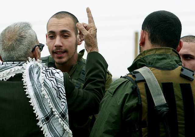 A Palestinian activist argues with Israeli army soldiers after building a tent in Jordan valley near the West Bank town of Tubas, Sunday, Feb. 2, 2014. Dozens of local and foreign activists have built a tent site northern Jordan valley over night called the Return village to symbolize the Palestinian refugees right for return and the Palestinians rights in the Jordan Valley. Israel demanded in US brokered peace talk a long security presence in the Jordan valley, the issue rejected by pedestrians who say its a major part of their occupied land and Israel must leave it in any peace deal. (AP Photo/Mohammed Ballas)