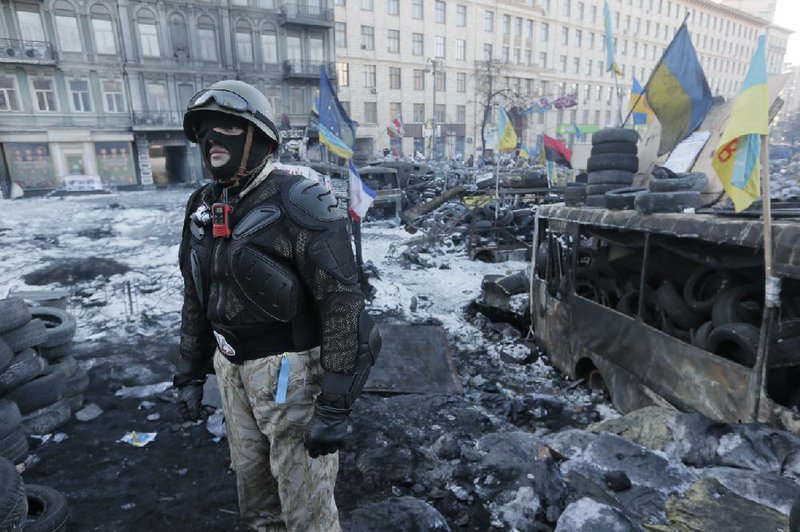 An opposition supporter guards a barricade in central Kiev, the epicenter of the country's current unrest, Ukraine, Sunday, Feb. 2, 2014. Kitted out in masks, helmets and protective gear on the arms and legs, radical activists are the wild card of the Ukraine protests now starting their third month, declaring they're ready to resume violence if the stalemate persists. (AP Photo/Efrem Lukatsky)