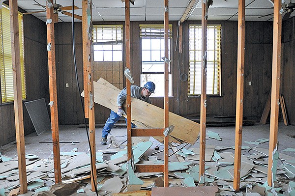 STAFF PHOTO SAMANTHA BAKER 
• @NWASAMANTHA 
Shane Shoemaker collects debris while gutting the former City Hall building Friday at the corner of West Elm Street and South Third Street in Rogers. The building will be converted into loft apartments with a wine and coffee bar, open to the public, in the basement.
