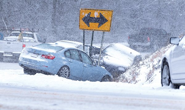 STAFF PHOTO BEN GOFF 
Several vehicles sit Sunday stuck in a ditch at a steep curve on East New Hope Road in Rogers.