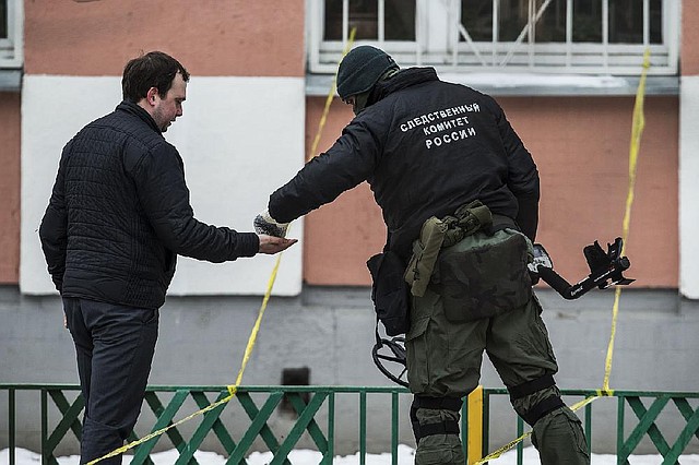 Russian investigative committee officers collect evidences a Moscow school on Monday, Feb. 3, 2014. An armed teenager burst into his Moscow school on Monday and killed a teacher and policeman before being taken into custody, investigators said. None of the children who were in School No. 263 were hurt, said Karina Sabitova, a police spokeswoman at the scene. The student also wounded a second police officer who had responded to an alarm from the school, she said. (AP Photo/Alexander Zemlianichenko)
