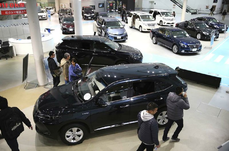 Visitors look at Toyota vehicles displayed Tuesday at a gallery in Tokyo. Toyota on Tuesday reported a quarterly profit of $5.2 billion, up from $984 million a year ago. 