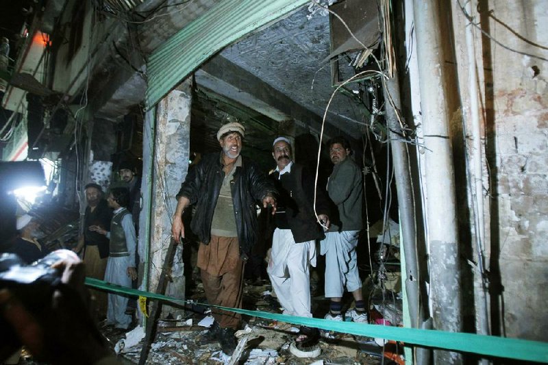 Pakistanis check the site of a suicide bombing near a Shiite mosque in Peshawar, Pakistan, on Tuesday. 