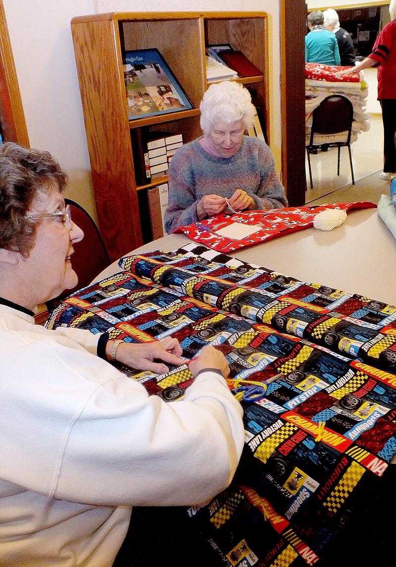 Cassi Lapp/The Weekly Vista Karen Box, left, and Dorothy Bowman of the Friendly Stitchers/Granny s of Bella Vista work on tying quilts during their bi-monthly meeting.