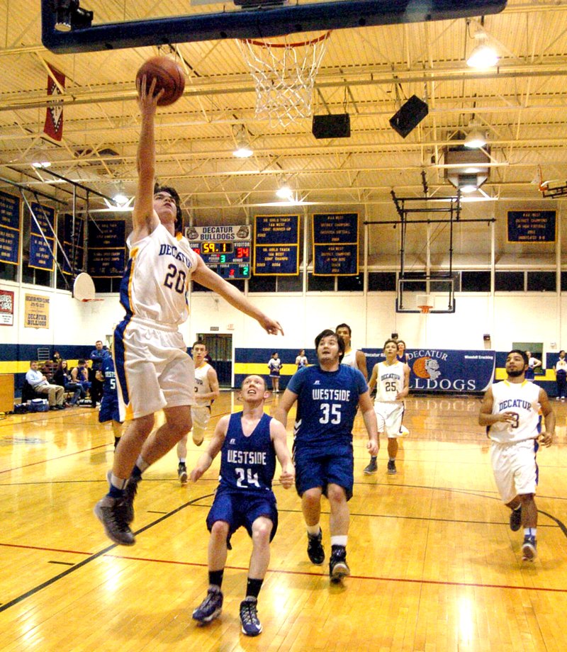 Photo by Mike Eckels Terry Kell (Decatur #20) flies through the air for a lay up during the Jan. 30 game with the Westside Rebels at Peterson Gym. Kell was the second leading scorer, with 13 points. The Bulldogs won the game, 66 to 44, and improve their record to 8 and 8 overall.