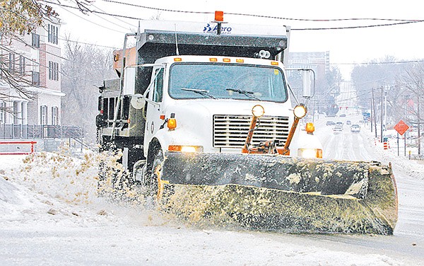 An Arkansas Highway and Transportation Department snow plow clears School Street Tuesday morning in south Fayetteville. Northwest Arkansas received a wintry mix of rain, sleet and snow throughout the day.