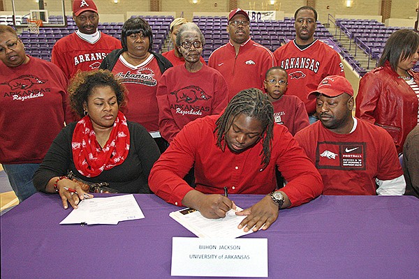 El Dorado High School defensive lineman Bijhon Jackson signs his letter-of-intent to play football for the University of Arkansas on National Signing Day at the EHS Wildcat Arena Wednesday. Jackson was surrounded by his mother Michelle, seated left, and father Anthony, seated right, many family members, classmates, teammates and coaches. 