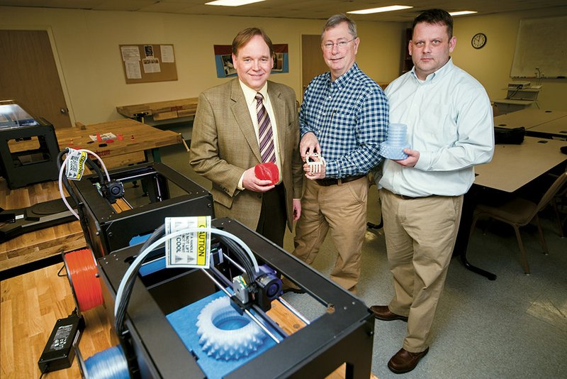 College of the Ouachitas President Stephen Schoonmaker, from the left, and instructors Glenn Franklin and Jody Callahan stand beside two of the more than 50 MakerBot 3-D printer/replicators the school has acquired for use by pre-engineering students.