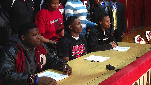 Flanked by teammates, Pine Bluff Dollarway athlete Josh Liddell (center) waits at a signing ceremony Wednesday, Feb. 5, 2013, in the Dollarway High School gym. Liddell signed with Arkansas. 