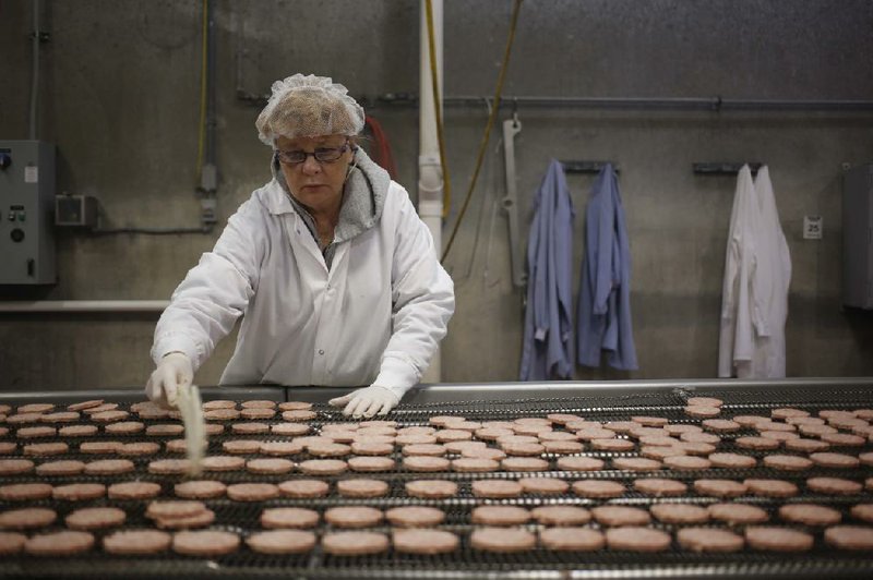 A quality-control worker watches pork sausage patties on an assembly line last year at the Purnell Sausage Co. factory in Simpsonville, Ky. The price of pork products is expected to increase this summer, the result of a virus that is killing pigs. 