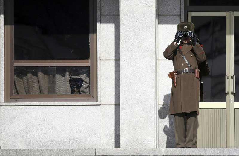 A North Korean soldier looks at southern side through a pair of binoculars at the border village of Panmunjom, South Korea, which has separated the two Koreas since the Korean War, on Thursday, Feb. 6, 2014. North Korea threatened Thursday to cancel a reunion later this month of Korean War-divided families because of forthcoming U.S.-South Korean military drills, causing frustration in Seoul only one day after the rivals agreed on dates for the emotional meetings. 